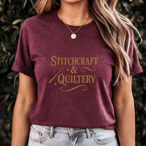 Woman styling our maroon graphic tee with phrase Stitchcraft & Quiltery. Cozy tee sold in the Hoops & Hoots Etsy shop. Perfect for wearing while you browse for September quilting inspiration! More colors and sizes available online.