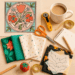 Bright collage of quilting materials inspired by floral tile designs, featuring colorful fabric bundles, sewing tools, and poppy-style patterns on a flat workspace.