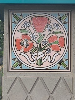 Decorative tile featuring red poppies and white flowers surrounded by green leaves, used as signage decor in Anaheim.