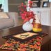 Quilted Halloween placemats styled with glitter candy corn and fall foliage in vase on a wooden coffee table