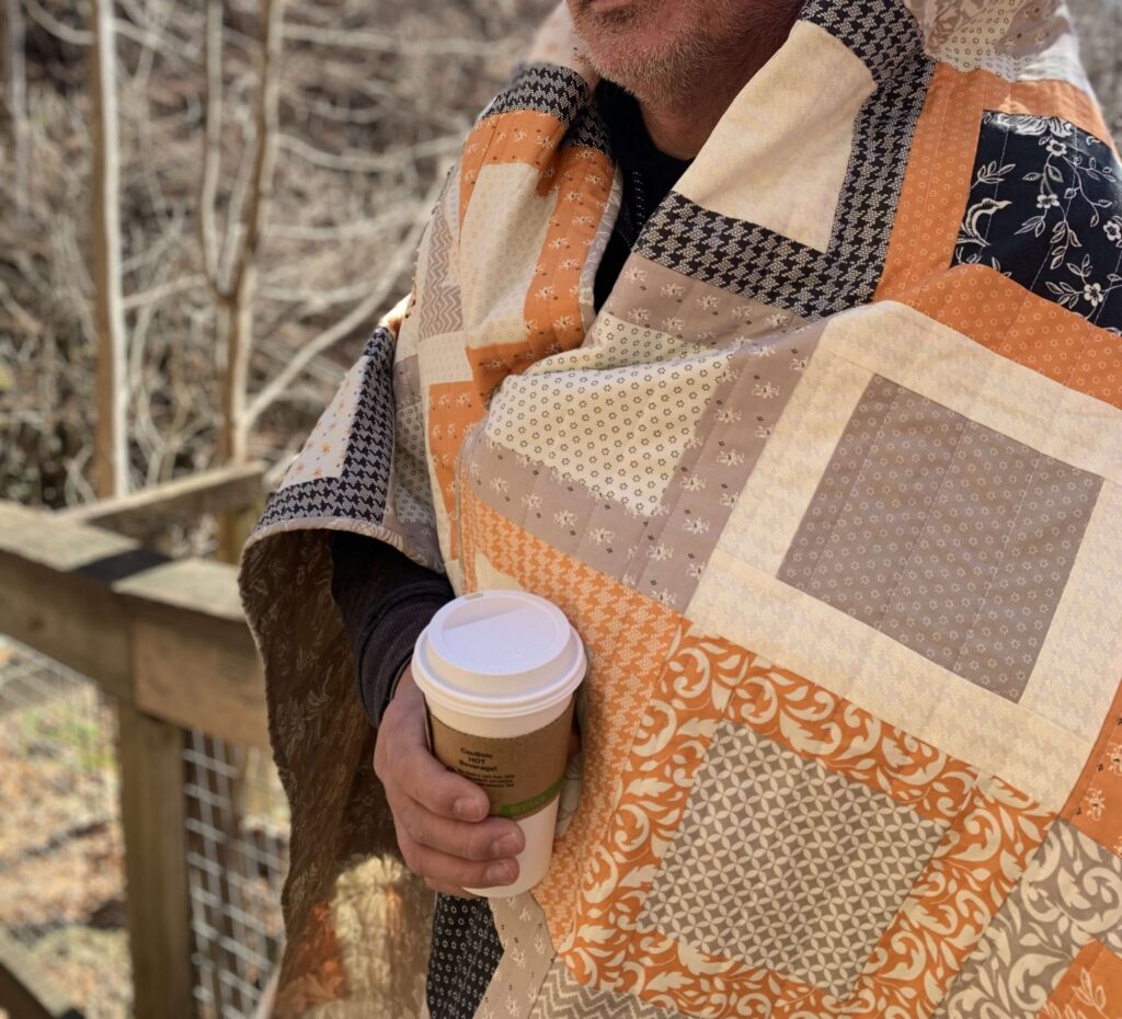Cozy Fall Framed Windows quilt draped over shoulders during a mountain morning reveal