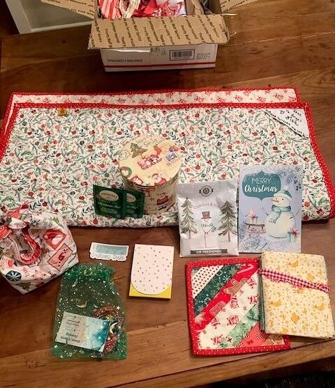 Collection of gifts received in a mini quilt swap, including a mini quilt and holiday-themed items.