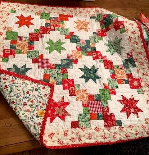 Mini quilt received in a Comfort & Joy quilt swap, displayed in a flat lay.