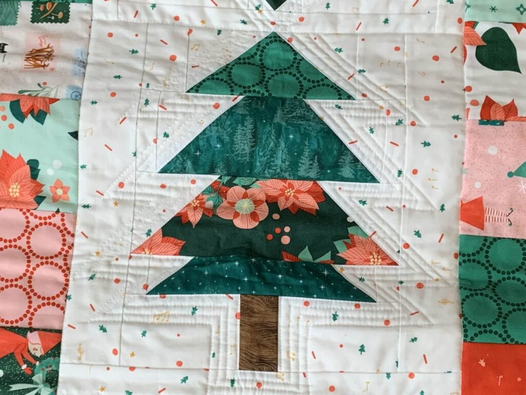Close-up of outline quilting on a Christmas tree quilt block from the Under the Pines table runner.