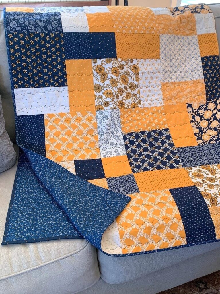 Layer cake loop quilt displayed on a sofa, showing patchwork layout