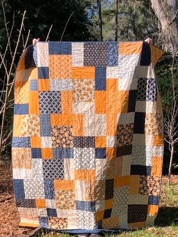 Handmade quilt held up outdoors showing full finished size
