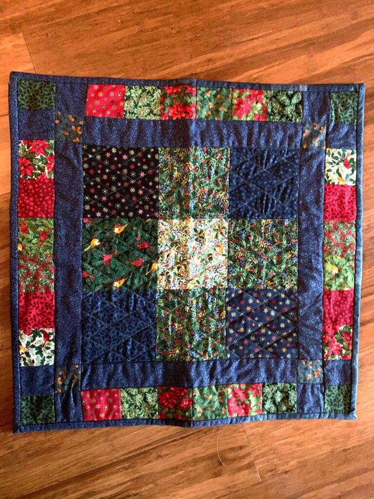 Square quilted table topper with patchwork center and dark border